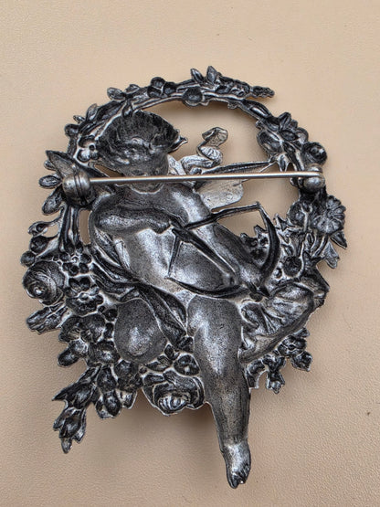 Silvertone Repousse Cupid With A Bow In A Floral Wreath Vintage 2.5" Brooch